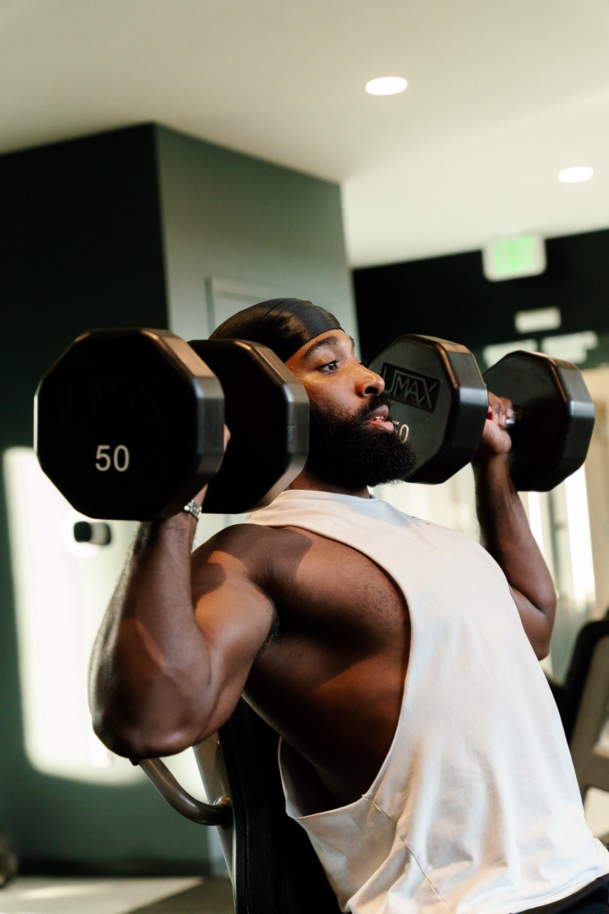 Sampson performing a dumbbell shoulder press for Day 2